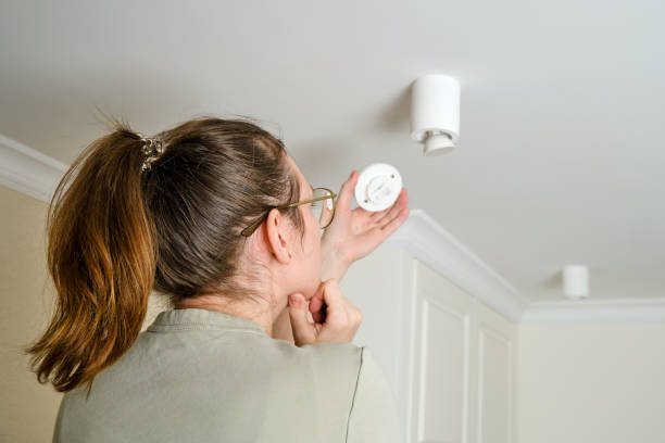 istock A woman changes a ceiling energy saving light bulb with LED light lamp in a home living room. Work at height self, diy 1372157467