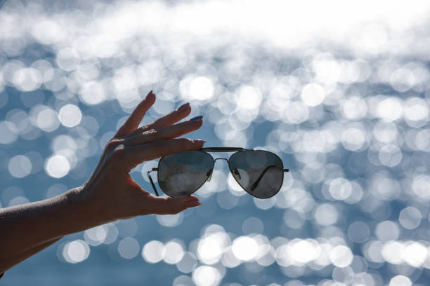 istock Sunglasses in a woman's hand against a blurred background with bokeh reflections 1372158704