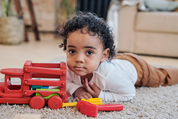 istock Curly-haired boy lying near toy car 1372158796