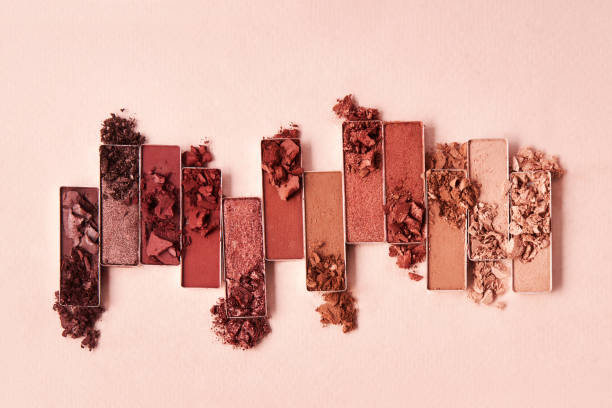 Flat lay of broken shimmering brown and nude eye shadow palette Flat lay of broken shimmering brown and nude eye shadow palette on a beige background. Cosmetic beauty product stage make up stock pictures, royalty-free photos & images