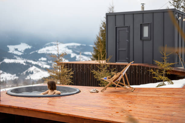 Woman swims in hot bath while resting at small modern house in the mountains stock photo