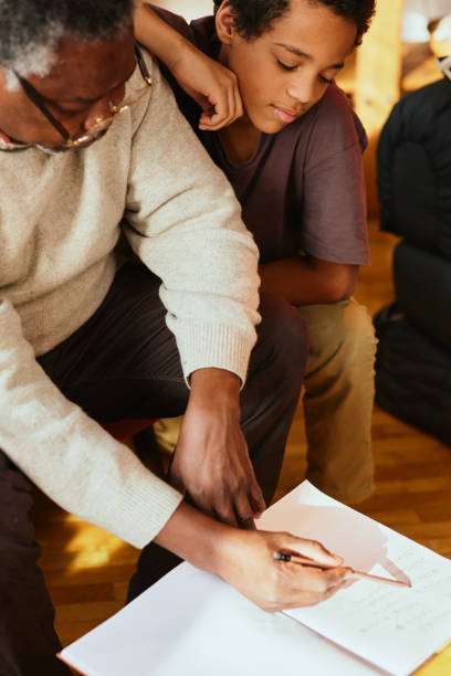 istock Grandfather checking on math problem for his grandchild at home. 1372161078