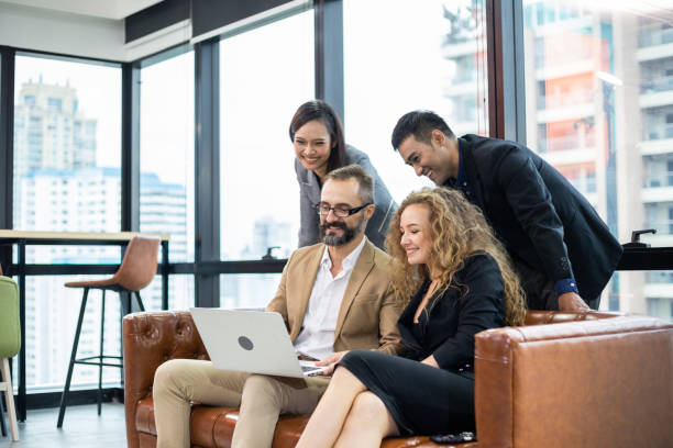 istock Group of cheerful businesspeople sitting on couch watching project on computer laptop. manager and colleagues brainstorming work together. business meeting conference in the office 1372162217