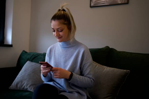 istock Young girl looking at cell phone, sitting on sofa 1372162218