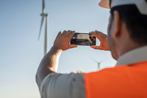 Electrical engineer / technician photographing wind farms with cell phone. Bom Jardim da Serra wind farm - Santa Catarina
