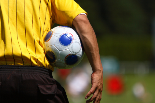 A soccer referee holding a soccer ball.