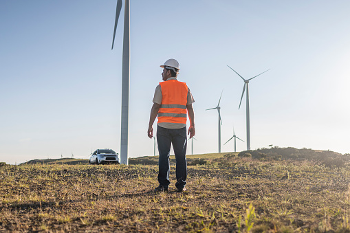 Electrical engineer/technician in open field contemplating wind farm landscape. Bom Jardim da Serra wind farm - Santa Catarina