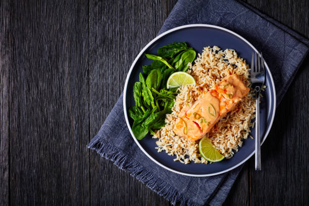 portion of cooked salmon with rice and greens - fruit sauce imagens e fotografias de stock