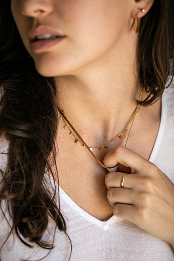 Close up of a young woman playing with a necklace that she is wearing around her neck