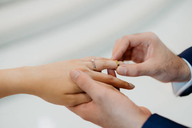 istock Bridegroom putting on a wedding ring into bride's finger 1372170055