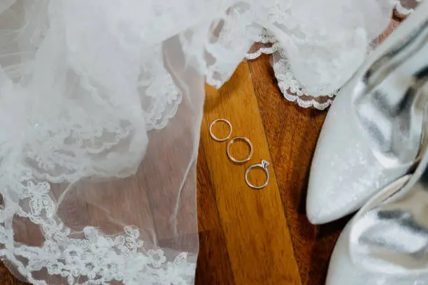 Photo of Wedding rings, wedding veil and wedding heels on wooden table
