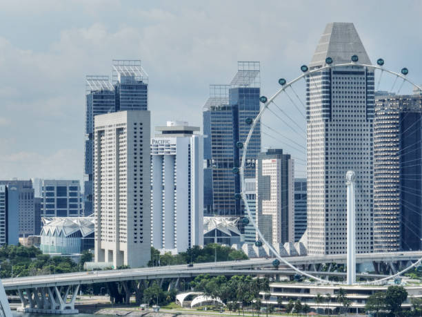 The Singapore Flyer Ferris Wheel seen during the day with financial district with crypto banks in the background. The Singapore Flyer Ferris Wheel is located in the middle of the city at Marina Bay.