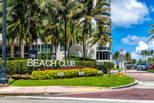 Sign entrance for Beach Club apartment condo building in Hallandale in Florida with palm trees on sunny day and blue sky Miami, USA - July 18, 2021: Sign entrance for Beach Club apartment condo building in Hallandale in Florida with palm trees on sunny day and blue sky 1 hotel south beach stock pictures, royalty-free photos & images