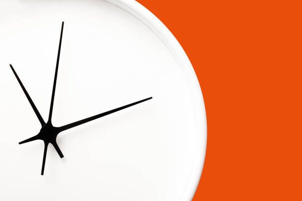 istock White round clock with black arrows isolated on orange background. 1372175383