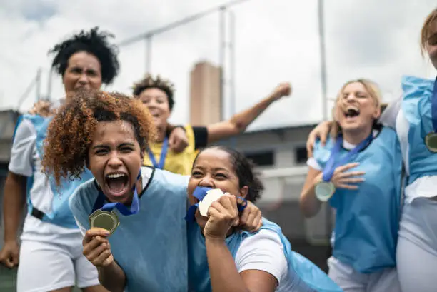 Photo of Female soccer players celebrating winning a medal