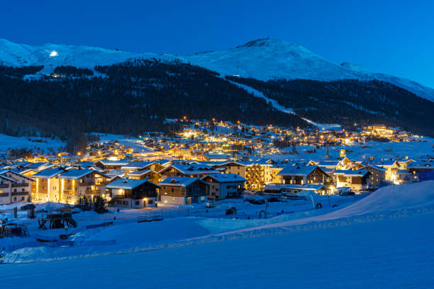 View of Italian village Livigno during twilight. Ski resort in winter time with snowcapped mountains and ski slopes in background stock photo