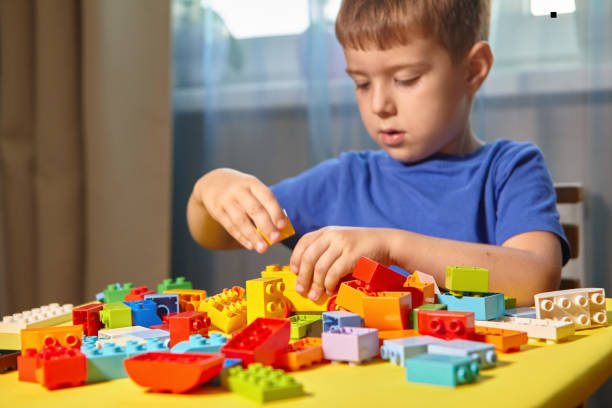istock A beautiful boy is playing at home with building blocks. A cute smiling boy is playing with a constructor with a lot of colorful plastic blocks in the room, building a city. Preschool classes. 1372176887