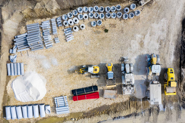 Aerial view of road roller, tractors, construction vehicles and construction materials.