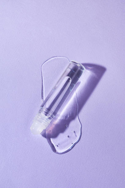 istock Transparent lip gloss in a roller ball bottles on a purple background. 1372178720