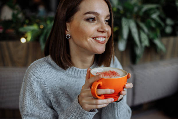 istock A young girl in a cafe drinks coffee from a bright orange mug 1372179126