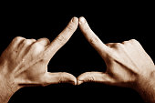 Triangle shape made with fingers. Two hands connected together background.