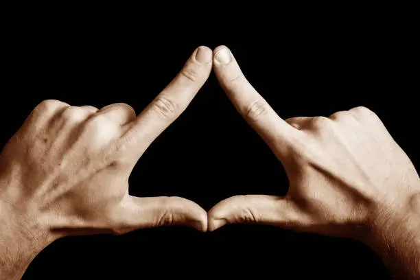 Illuminati triangle. Fingers sign isolated on black.