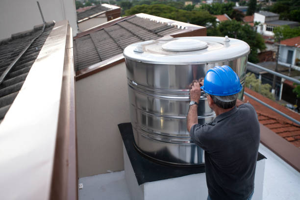Portrait of an engineer inspecting a water storage tank on a dwelling rooftop.\