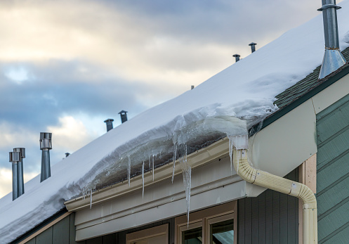 Winter icicles hanging from a roof covered by the snow of a wooden house in Fraser, Colorado