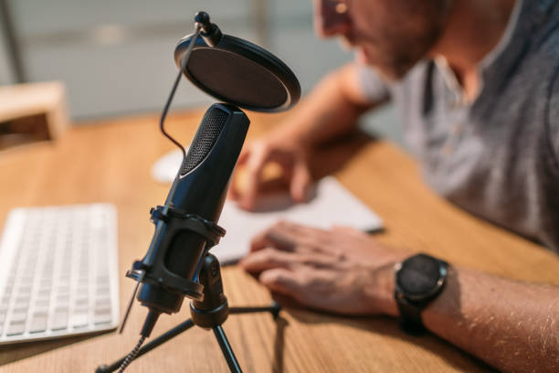 mikrofon mit pop-filter nahaufnahmefoto mit einem mann, der den text liest und die stimme mit einem desktop-computer aufnimmt. modernes home-sound-studio-audioaufnahme- oder online-streaming-technologiekonzept. - microphone mid air recording studio radio station stock-fotos und bilder