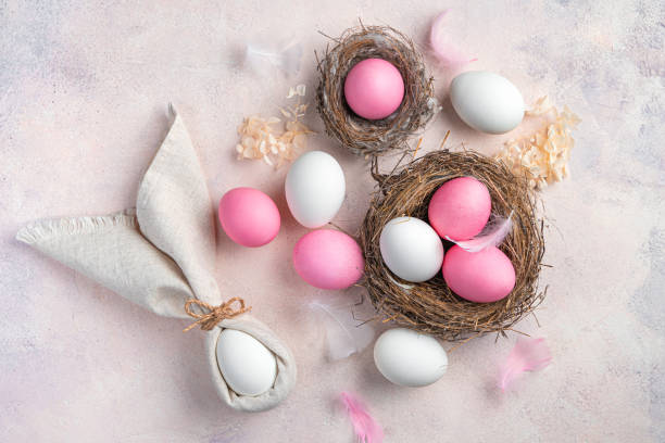 istock Easter background with pink and white eggs and an Easter bunny from a napkin on a light pink background 1372182095