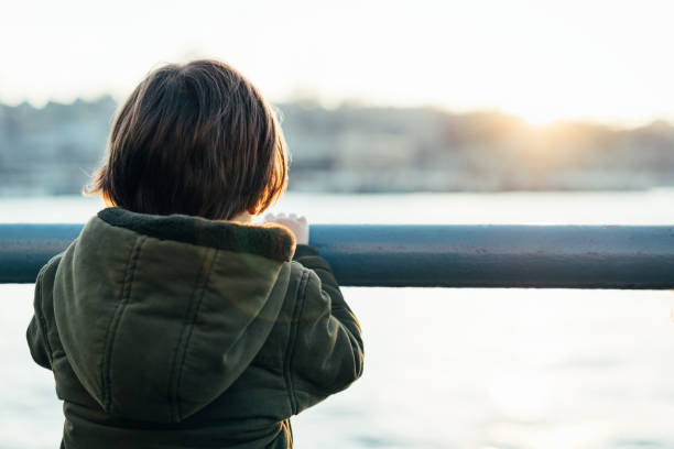 istock Little boy watching the sea from the coast at sunset 1372182098