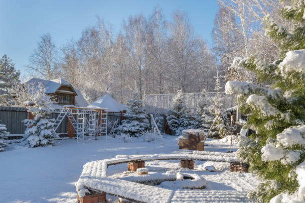 Garden after heavy snowfall in early winter. Trees, cedar, benches and playground are covered with fresh snow. All around it became light and fresh. Lifestyle, care and relaxation