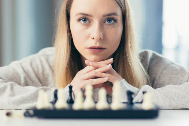 ritratto fotografico in primo piano di giovane bella donna che gioca a scacchi a casa, studia, pensa, competizione, quarantena - concentration chess playing playful foto e immagini stock