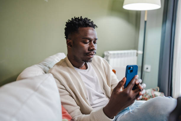 istock Young African-American man using mobile phone at home 1372186129