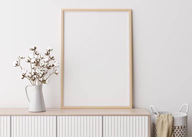 istock Empty vertical picture frame on white wall in modern living room. Mock up interior in minimalist, scandinavian style. Free space for picture. Console, rattan basket, cotton plant in vase. 3D rendering 1372187136