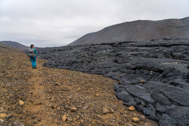 Tourist hiking at smocking black lava from volcano Fagradalsfjall stock photo