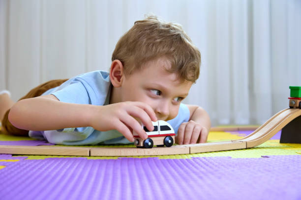 istock Funny boy 4-5 years old looks into the camera and plays with a train 1372188507