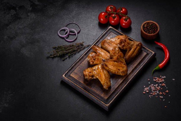 istock Baked chicken wings with vegetables and spices on a black background 1372193128