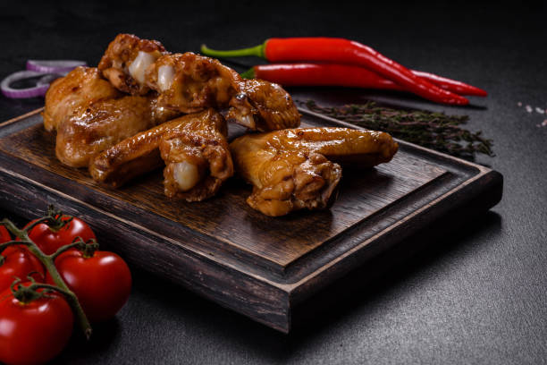 istock Baked chicken wings with vegetables and spices on a black background 1372193147