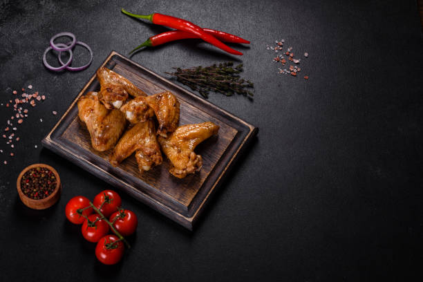 istock Baked chicken wings with vegetables and spices on a black background 1372193158