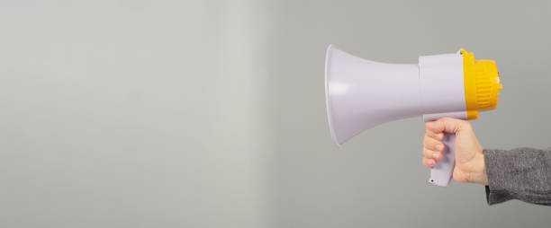istock A hand is holding megaphone and  wearing a dark grey T-shirt on grey background. 1372193220