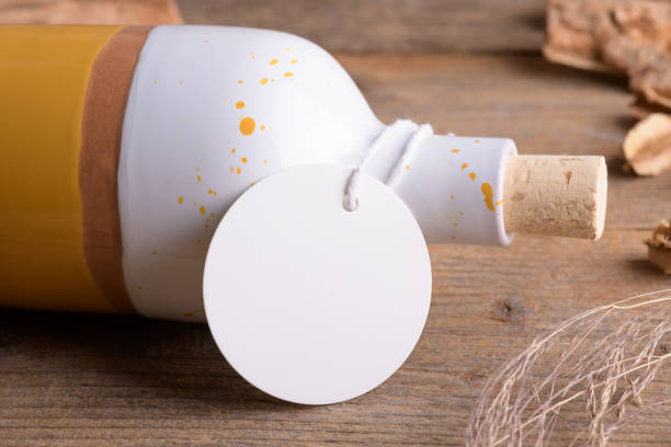 istock Round white tag mockup on ceramic bottle for olive oil a wooden background with boho decoration, element for packing 1372193357