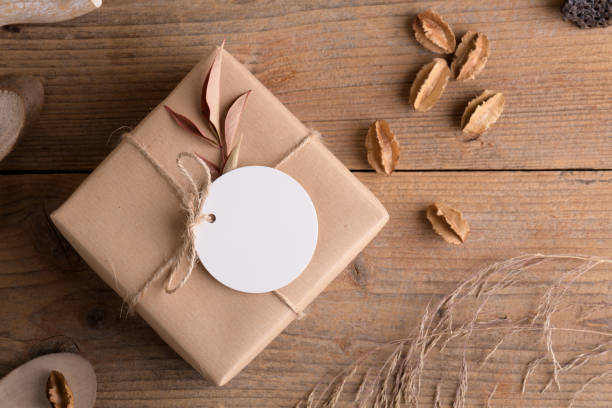 istock Round white gift tag mockup on craft wrapped presents on rustic wooden background with boho decoration 1372193372