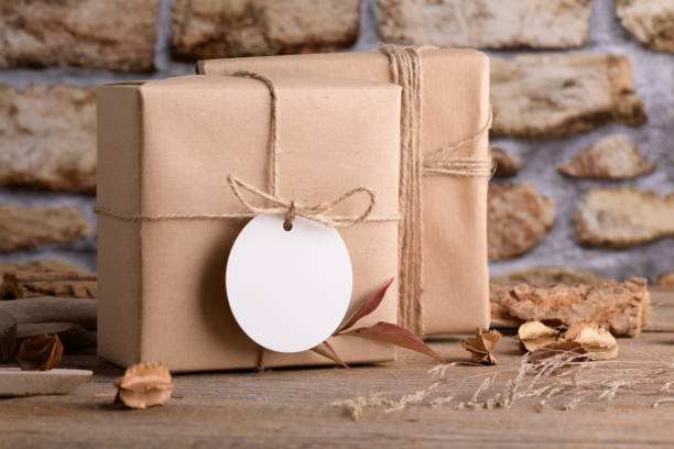 istock Round white gift tag mockup on craft wrapped presents on rustic wooden background with boho decoration 1372193375