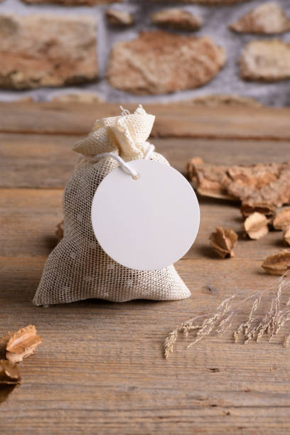 istock Round white gift tag mockup on gift packet on rustic wooden background with boho decoration. 1372193381
