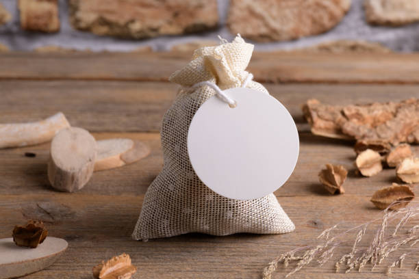 istock Round white gift tag mockup on gift packet on rustic wooden background with boho decoration. 1372193385