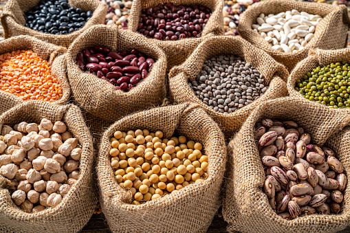 Assorted legumes in burlap sacks in a row as a full frame background