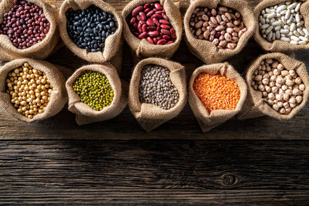 istock Assorted legumes in burlap sacks in a row leaving a copy space of rustic wood board 1372197981