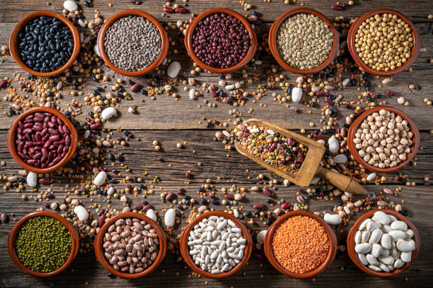 istock Assorted legumes in round clay containers on rustic wooden background frame shape with center copy space 1372200000