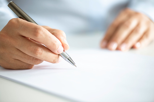 Close up of an unrecognizable businessman signing contract paper.
